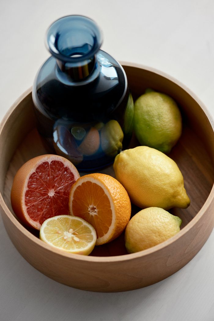 about-us Blue glass bottle with mixed citrus fruits in a wooden bowl, vibrant and fresh composition.
